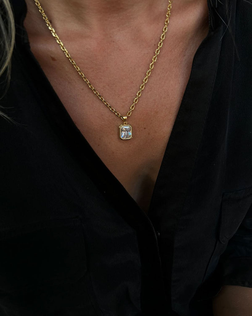 close up on a gold crystal necklace on a model
