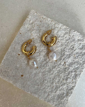 pearl dangle earrings on a stone piedestal