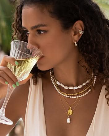 model sipping wine wearing a set of five necklaces