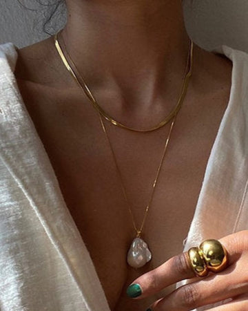 woman's neck and cleavage wearing white linen blouse with gold and pearl necklaces 